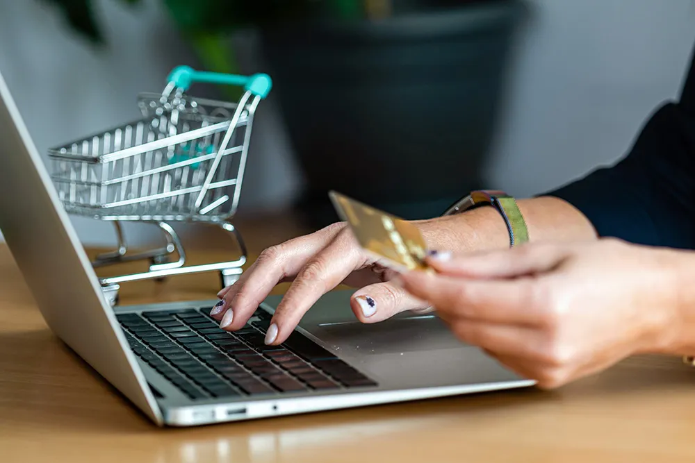 woman typing on laptop and holding a credit card