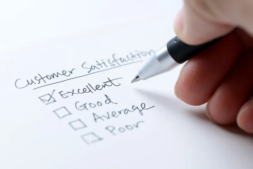 person filling out a customer satisfaction survey with pen a and paper