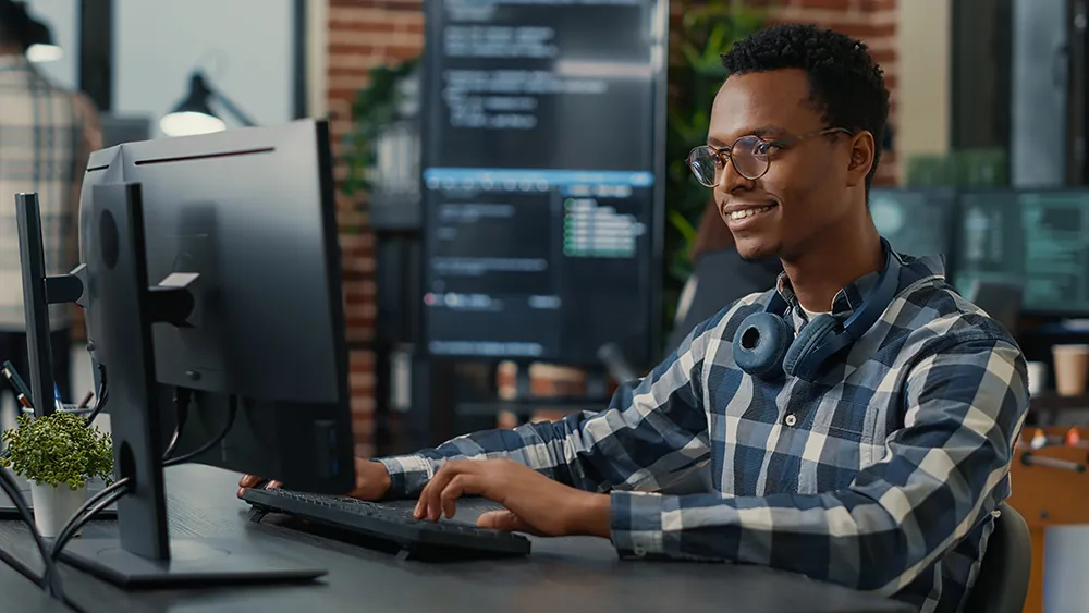 man sitting at desk typing on computer