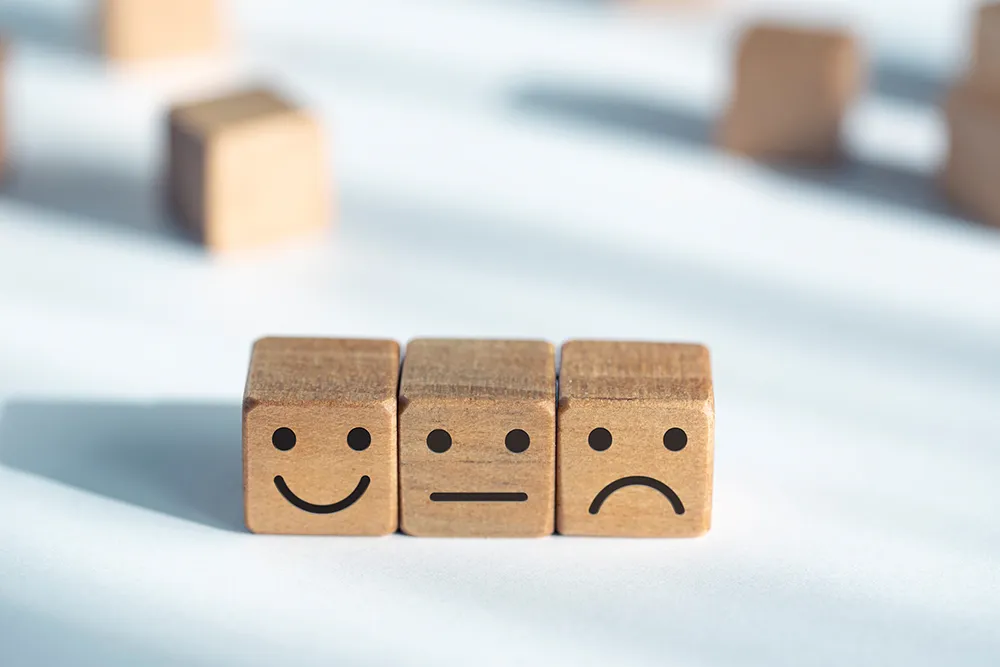 three wooded cubes lined up with different expression on them