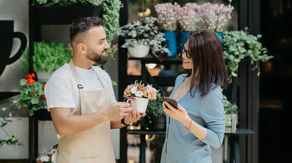 man giving a pot of flowers to a woman