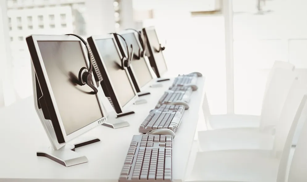 row of monitors and keyboards sitting on a desk